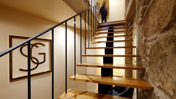 Una escalera moderna con escalones de madera y barandillas de metal, que conduce a un piso superior.