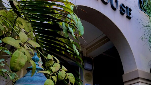 A traditional street lamp with a glowing light, a black metal railing, and a building entrance with an archway. - Capernaum Hotels (Kampala)
