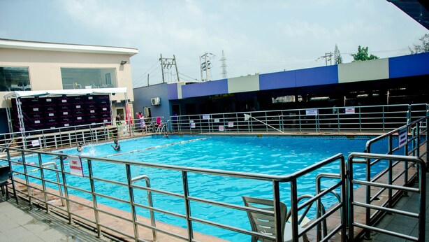 En swimmingpool med ett metallräcke, en hoppställning och en livräddarstol.
