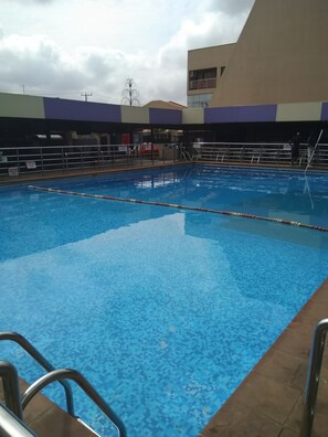 A swimming pool with clear blue water, surrounded by a tiled deck and metal railings. - Havannah Suites & Conference Centre (Lagos)