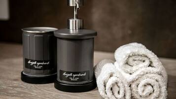 Two black candle containers labeled "donzette apartments" and a rolled white towel on a wooden surface.