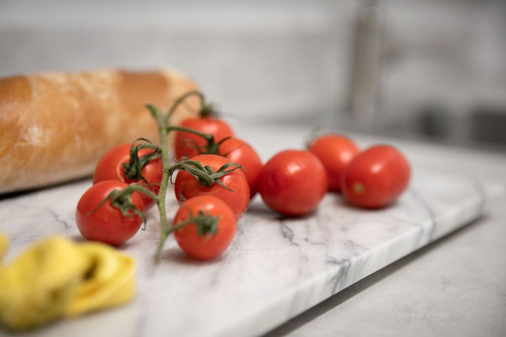 Eine Marmarbeplatte mit einem Brot und Kirschtomaten.