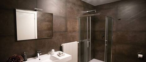 A modern bathroom with a white vanity, a glass shower enclosure, and a large mirror.
