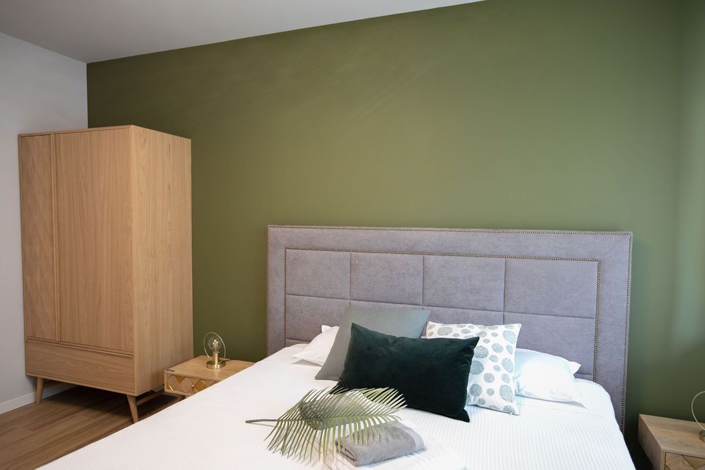 Una camera da letto con un letto, un comodino, un armadio e una parete verde.