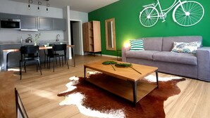 A modern living room with a wooden coffee table, a grey sofa, and a green wall with a white bicycle decoration. - Donizetti Residence (Bergamo)