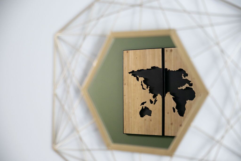 Een houten wereldkaart op een wand met zeshoekig mozaïek.