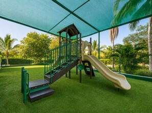 A playground with a slide, climbing steps, and a covered area.