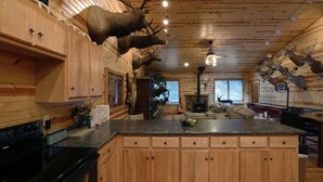 A cabin interior with wooden walls, a central island, and mounted animal heads. - Edenwood Ranch Private SQ MILE (Wautoma)