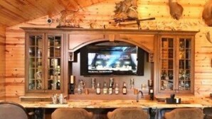 A wooden bar area with a television screen, bar stools, and shelves with bottles. - Edenwood Ranch Private SQ MILE (Wautoma)