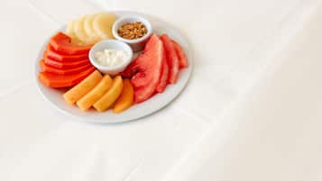 Un plato con frutas cortadas y un tazón pequeño de granola.