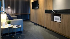 Cocina moderna con armarios de madera, microondas integrado y televisor de pantalla plana en la pared.