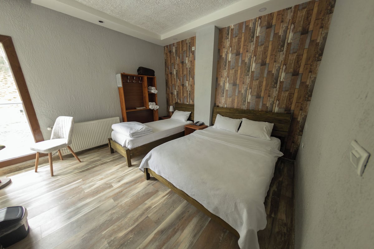 A bedroom with two beds, a wooden wardrobe, a chair, and a radiator.