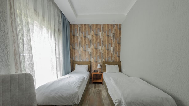 Una habitación con dos camas, una mesita de noche de madera, una lámpara y una silla.