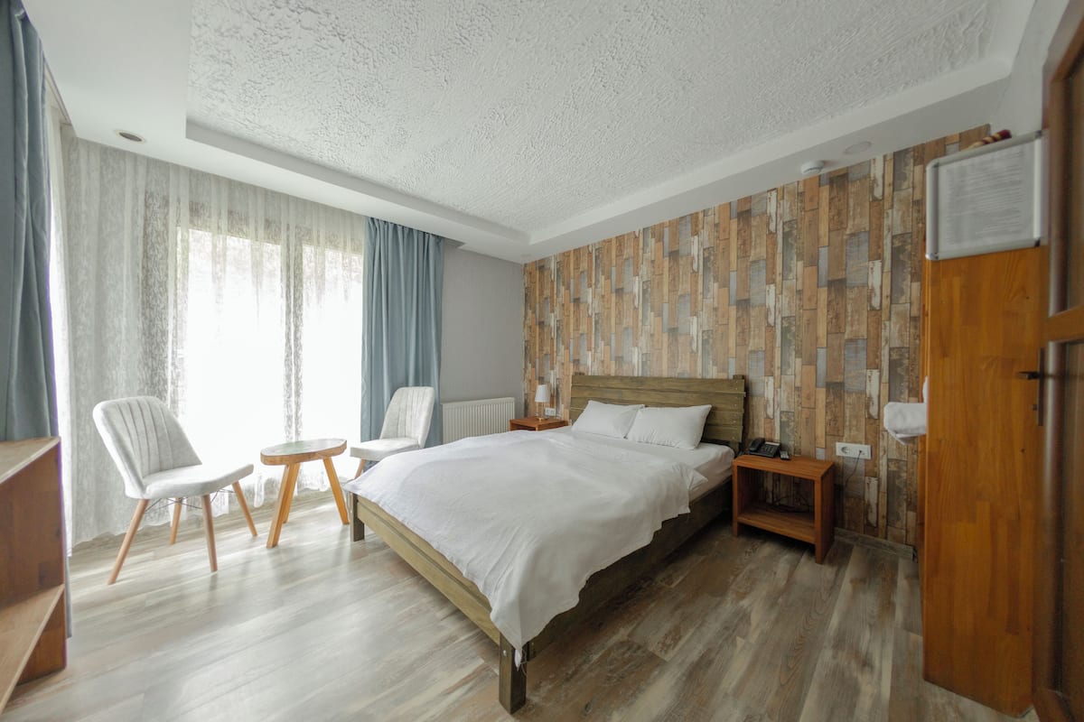 A bedroom with a wooden bed, two chairs, a small table, and a nightstand.