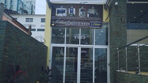 The entrance to Vila das Águas Hotel with a modern facade, glass doors, and a sign indicating room rates. - Vila das Acácias (Maputo)