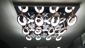A modern interior with a unique chandelier design, a staircase, and a window with blinds. - Vila das Acácias (Maputo)