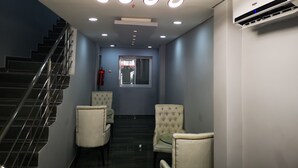 A modern interior with a staircase, two upholstered chairs, a glass table, and a ceiling light fixture. - Vila das Acácias (Maputo)