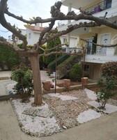 Un patio con un árbol, senderos de grava y un edificio con balcones.