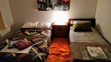 Ein Schlafzimmer mit zwei Betten, einem Nachttisch, einem Teppich und einem Wandbild.