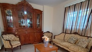 Una sala de estar con un aparador de madera, dos sillones, un sofá y una mesa de centro.