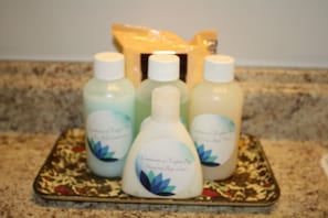 A tray with four bottles of hand and body lotion on a patterned tray.