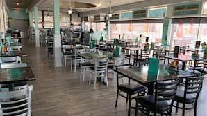 Un ristorante con diversi tavoli e sedie, una zona bar e ampie finestre.