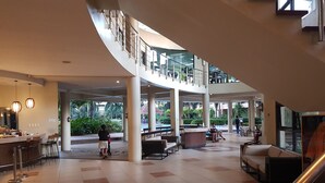 A spacious lobby with a curved staircase, seating areas, and a reception desk.