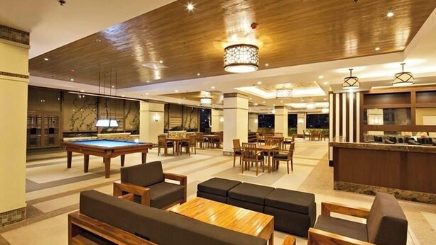 A spacious lobby with a pool table, comfortable seating, and a bar area.