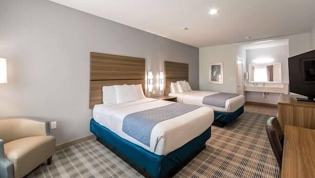 A hotel room with two beds, a TV, a desk, and a chair. - Porter Inn (Porter)