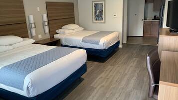 A hotel room with two beds, wooden headboards, a painting, a desk, and a chair.