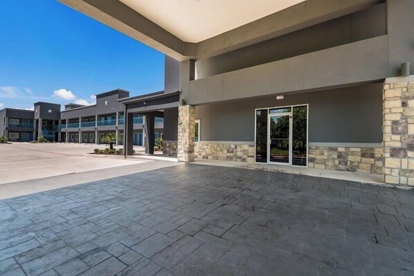 A modern building with a covered entrance, stone accents, and a clear sky.