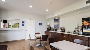 A modern kitchen with a white countertop, wooden cabinets, and a dining area with a white table and chairs. - Porter Inn (Porter)