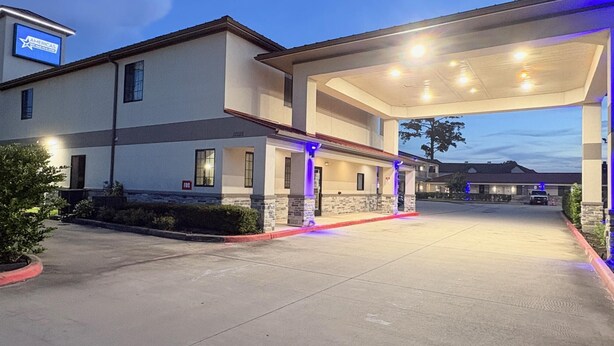 A modern building with a covered parking area and a sign for AMERICAS. - Americas Best Value Inn & Suites Houston Veterans Memorial (Houston)
