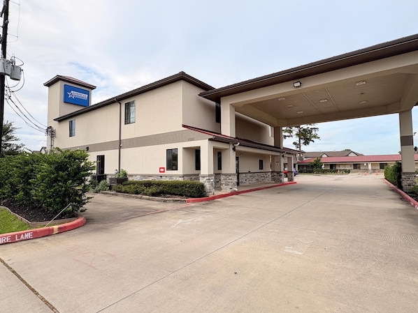 A modern hotel with a gas station attached. It features a flat roof, a blue sign on the building, and a paved parking area. - Americas Best Value Inn & Suites Houston Veterans Memorial (Houston)