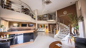 A modern hotel lobby with a reception desk, seating area, and a staircase leading to an upper level. - Rapport Hotel (Juazeiro)