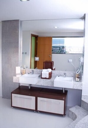 A modern bathroom with two sinks, a large mirror, and a wooden vanity.