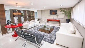 A modern living room with a white sofa, red round table, and a glass coffee table. - Rapport Hotel (Juazeiro)