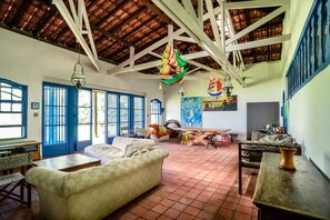 A spacious room with a high ceiling, a large window, and a tiled floor. - Ilha Bela a Beira Mar (Ilhabela)