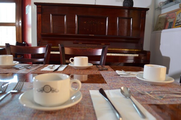 A dining table set with white cups and saucers, cutlery, and a placemat. - Hotel Casa Franco (San Pedro y San Pablo Teposcolula)