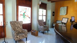 Zona de recepción con dos sillones estampados, un mostrador de madera y una obra de arte en la pared.