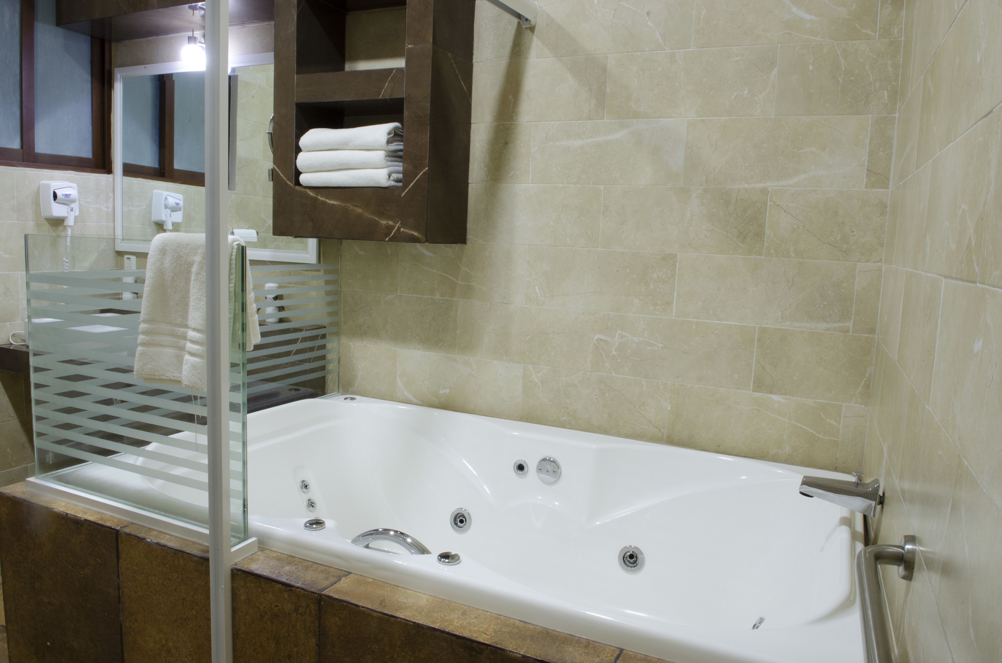 Une salle de bain moderne avec une douche à parois de verre, une baignoire blanche et un mur recouvert de carreaux de marbre.