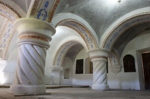 An interior with arched ceilings and columns, featuring intricate patterns and a plain floor.