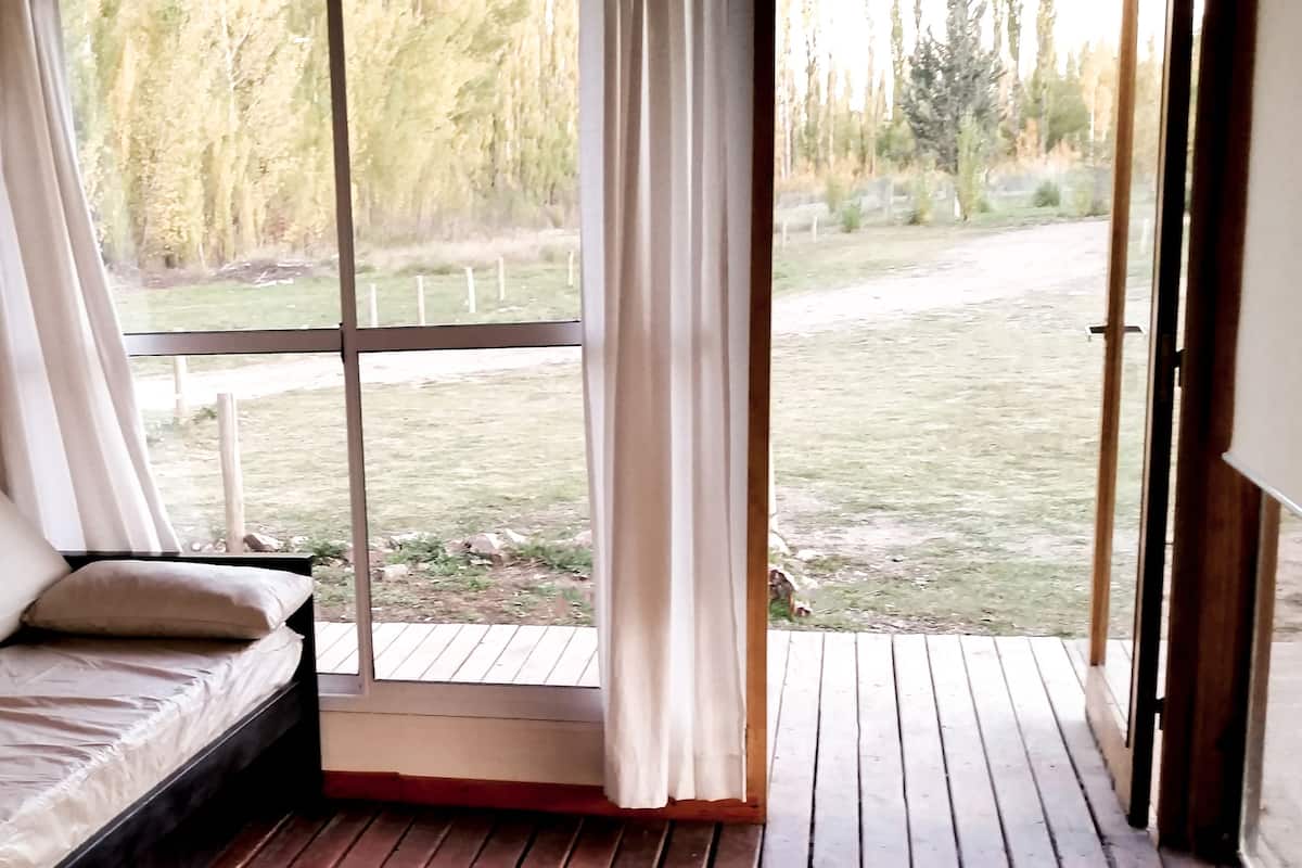 Una habitación con cama, ventana y vista a un área con césped.