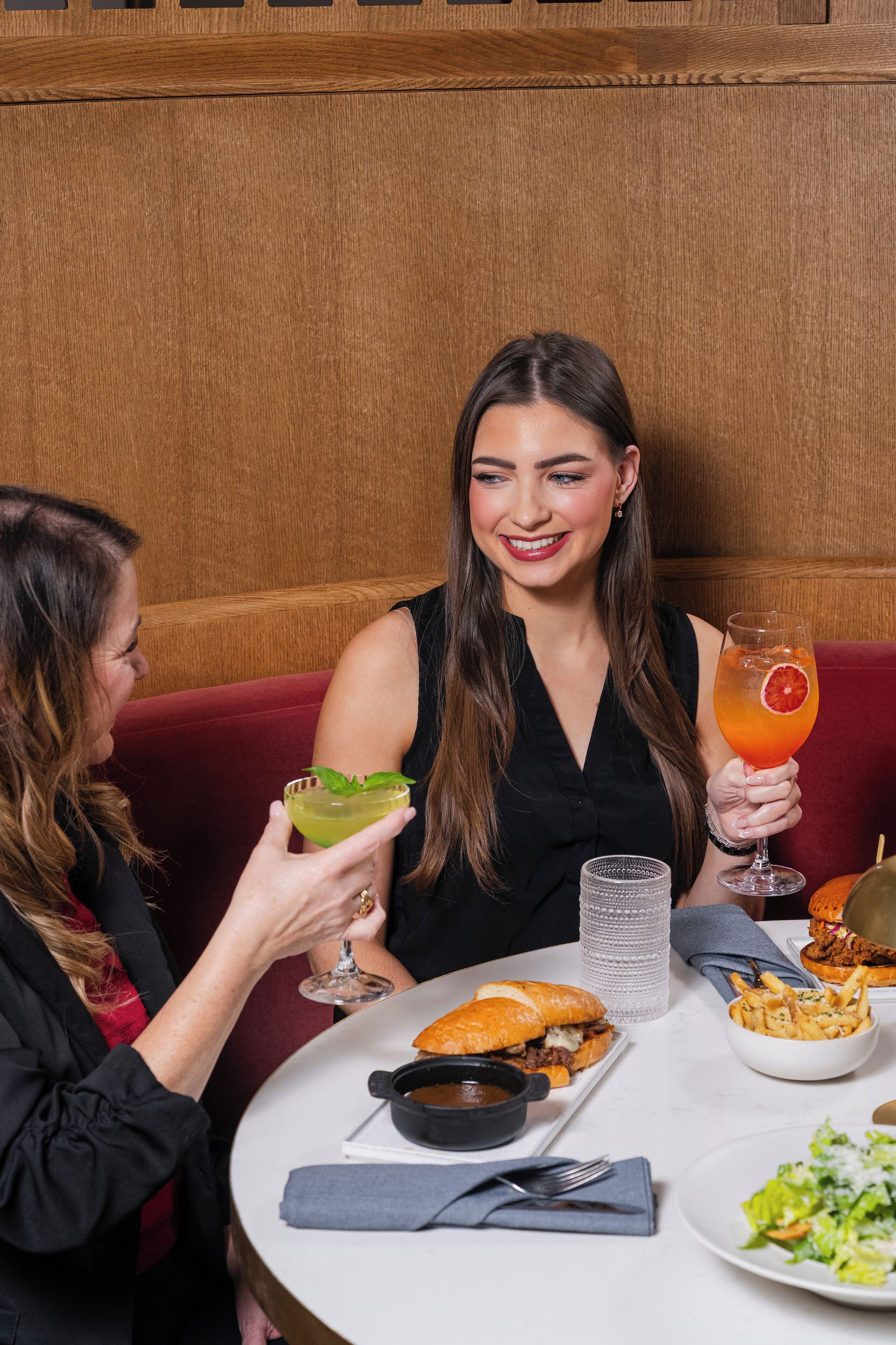 A dining table with a sandwich, fries, salad, and a drink.