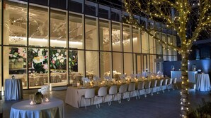 A banquet hall with a long table set for a formal event, large windows, and decorative lighting. - HALL Arts Hotel, Dallas, Autograph Collection (Dallas)