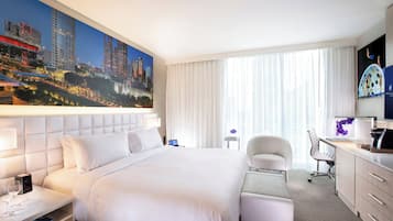 Camera d'albergo con un letto grande, una scrivania, una sedia e un affresco con una vista sulla città.