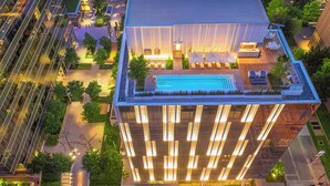 A modern hotel with a rooftop pool, surrounded by greenery and illuminated by vertical lights. - HALL Arts Hotel, Dallas, Autograph Collection (Dallas)