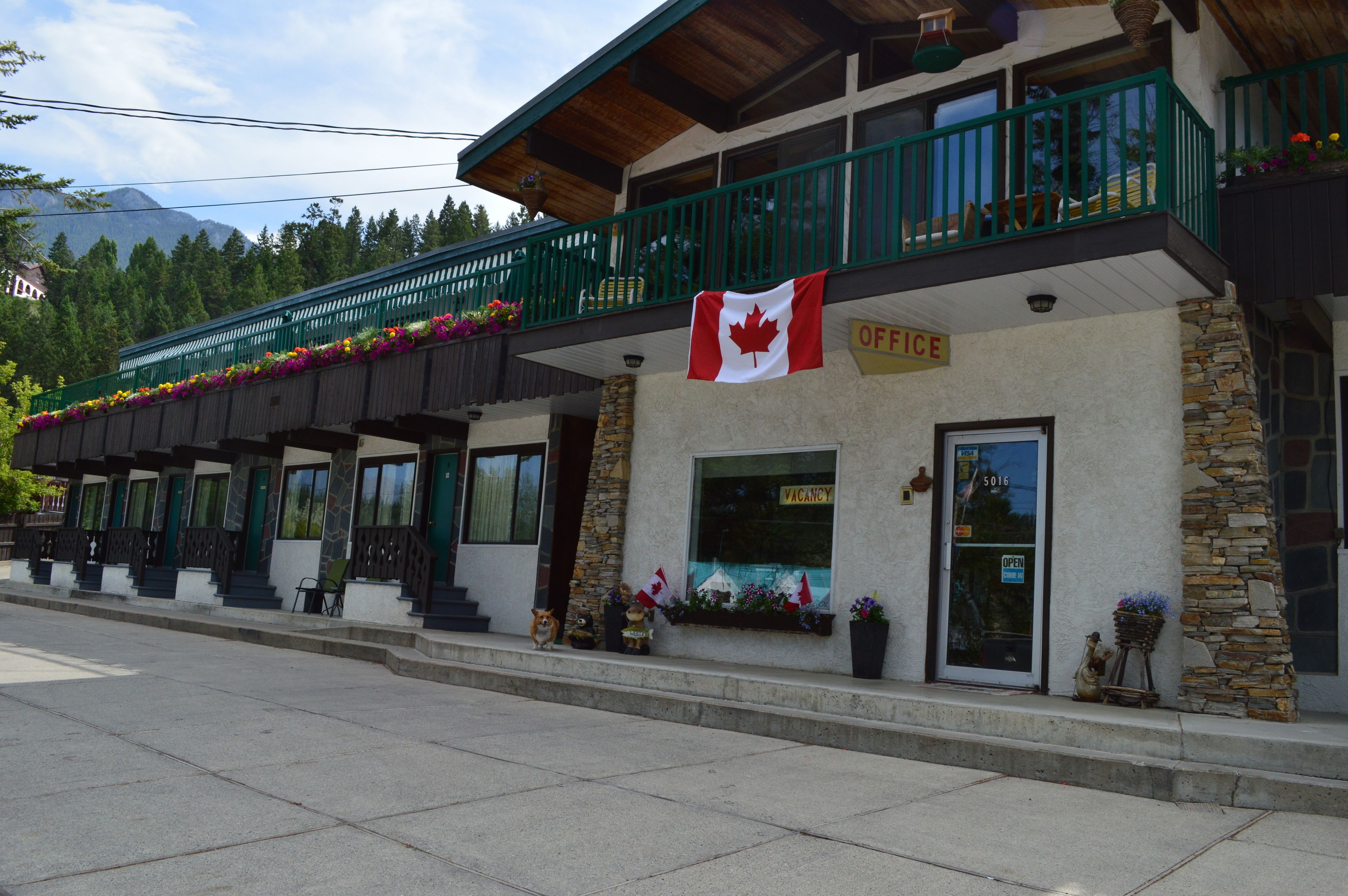 Een gebouw met een Canadese vlag, een bord dat een kantoor aangeeft en een raam met een 'VACANCY'-bord.