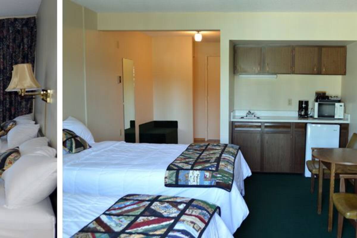 Ein Hotelzimmer mit zwei Betten, einem Schreibtisch, einem Stuhl, einem Fernseher und einer Küchenzeile.