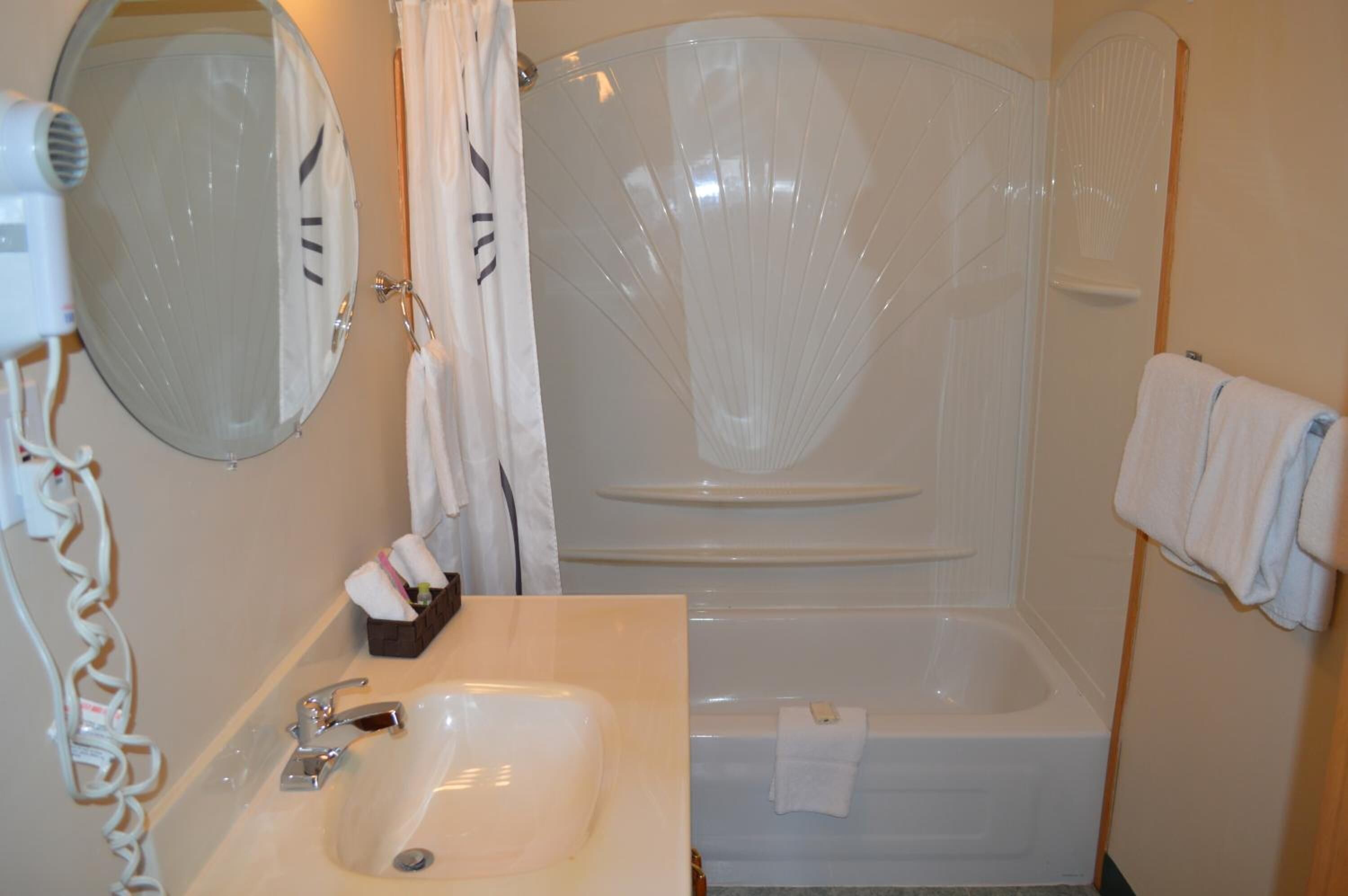 Une salle de bain équipée d’un lavabo, d’un miroir, d’une douche et d’un porte-serviettes.